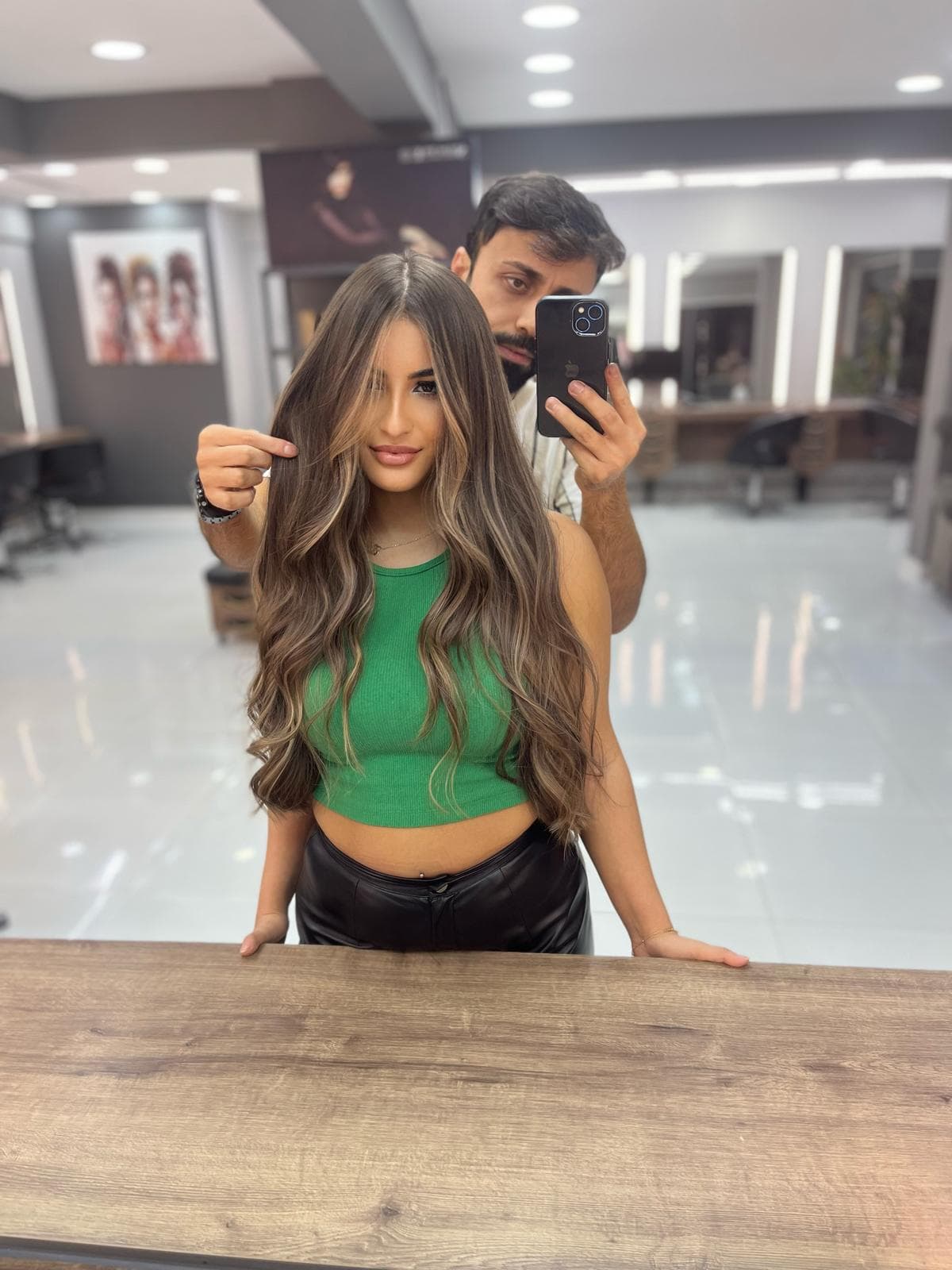 Karamel balyaj — ayna selfie'si, stilist arkada telefonla